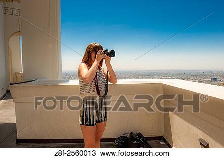 Young woman taking a photo on the balcony at the Griffith Observatory in Los Angeles, California. View Large Photo Image Stock Image - Young woman taking a photo on the balcony at the Griffith Observatory in Los Angeles, California.. Fotosearch