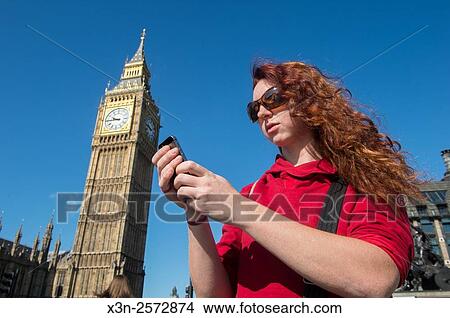Young woman texting on her cell phone in front of Big Ben in London, England. View Large Photo Image Picture - Young woman texting on her cell phone in front of Big Ben in London, England.. Fotosearch