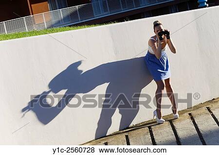 Stock Photo - Young woman with binoculars cast big shadow on wall. Fotosearch