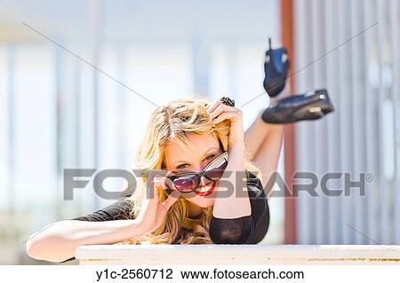 Stock Image - Young woman with bright Red lips flirting lying on tummy. Fotosearch