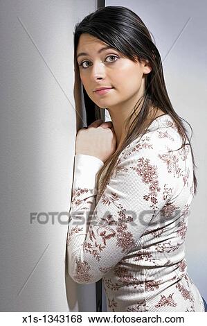Young woman with long hair leans against a wall and turns her head to the viewer. View Large Photo Image Stock Photo - Young woman with long hair leans against a wall and turns her head to the viewer.. Fotosearch