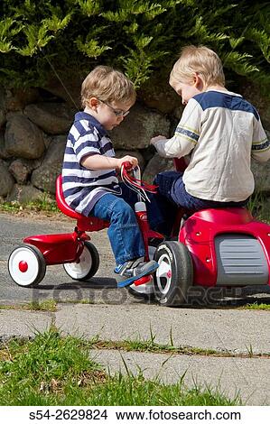 A boy runs into his brother on a tricycle outdoors. View Large Photo Image Picture - A boy runs into his brother on a tricycle outdoors.. Fotosearch