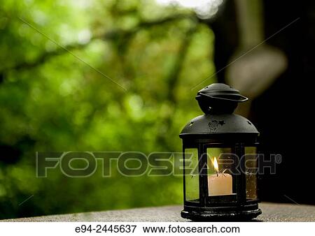Stock Photo - A lighted candle in a lantren on a stone wall in a garden. Pittsburgh Pennsylvania USA. Fotosearch