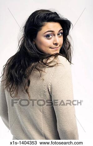 A long haired, pretty girl dressed in a beige sweater looks back toward the camera her her head tilted toward one shoulder, with a pretty smile on her face. View Large Photo Image Stock Image - A long haired, pretty girl dressed in a beige sweater looks back toward the camera her her head tilted toward one shoulder, with a pretty smile on her face.. Fotosearch