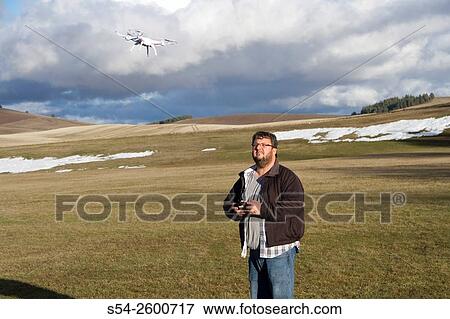 A man flying a small drone outdoors in Spokane county, USA. View Large Photo Image Stock Photo - A man flying a small drone outdoors in Spokane county, USA.. Fotosearch