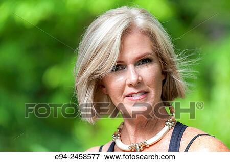 A portrait of a 56 year old blond woman looking directly at the camera, outdoors.. View Large Photo Image Stock Photo - A portrait of a 56 year old blond woman looking directly at the camera, outdoors... Fotosearch