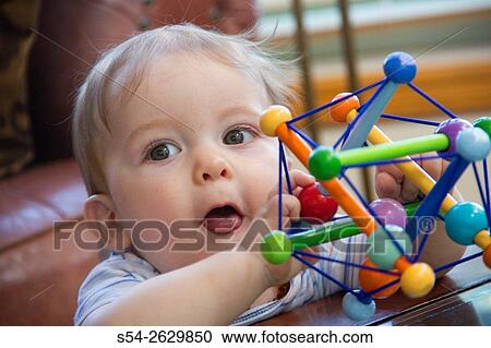 A toddler playing with a colorful toy indoors. View Large Photo Image Stock Image - A toddler playing with a colorful toy indoors.. Fotosearch