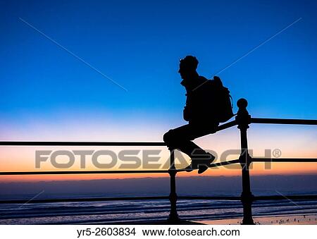 A walker on the England Coast Path at sunrise at Seaton Carew on the north east coast of England. United Kingdom. View Large Photo Image Picture - A walker on the England Coast Path at sunrise at Seaton Carew on the north east coast of England. United Kingdom.. Fotosearch