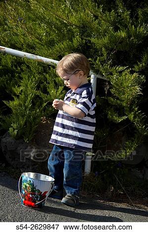 A young boy inspecting his Easter candy after a hunt. View Large Photo Image Stock Photo - A young boy inspecting his Easter candy after a hunt.. Fotosearch
