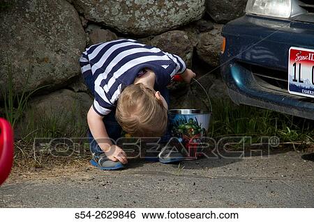 Stock Photograph - A young boy looking for Easter eggs during a hunt.. Fotosearch