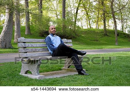 Picture - A young businessman sits on a park bench in Spokane, Washington, USA.. Fotosearch