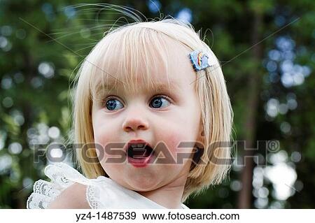 A young caucasian toddler outdoors with a surprised expression on her face. View Large Photo Image Stock Photo - A young caucasian toddler outdoors with a surprised expression on her face.. Fotosearch