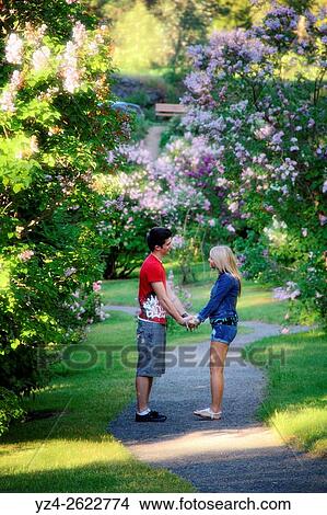 Picture - A young couple together outdoors in a lilac garden.. Fotosearch