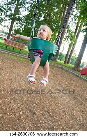 A young female toddler swinging in a child swing at a park in Spokane, Washington, USA. View Large Photo Image Stock Photograph - A young female toddler swinging in a child swing at a park in Spokane, Washington, USA.. Fotosearch