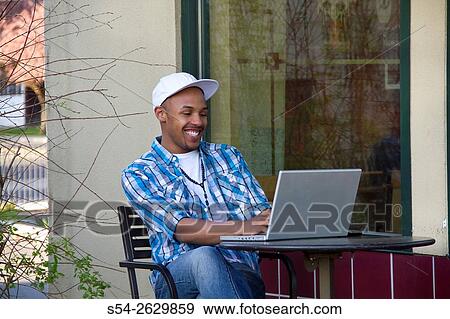 Stock Photo - A young man working on a laptop in Spokane, Washington.. Fotosearch