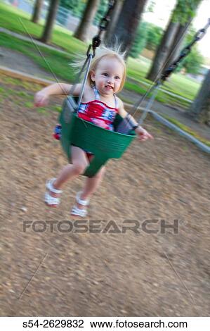 A young toddler in a swing at the park in Spokane, Washington, USA. View Large Photo Image Stock Image - A young toddler in a swing at the park in Spokane, Washington, USA.. Fotosearch