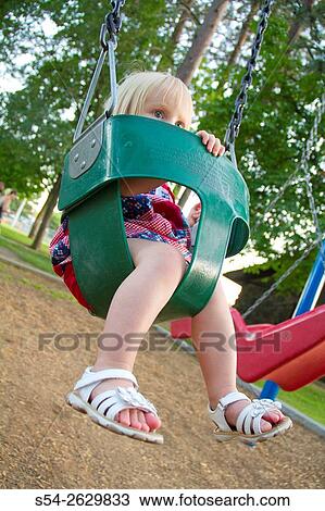 Stock Image - A young toddler in a swing at the park in Spokane, Washington, USA.. Fotosearch