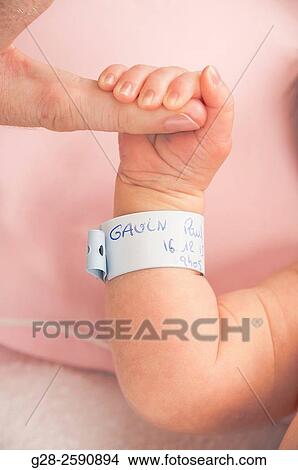 Adult, father's finger holding baby boy? s hand and arm with birth identification name band View Large Photo Image Picture - Adult, father's finger holding baby boy? s hand and arm with birth identification name band. Fotosearch