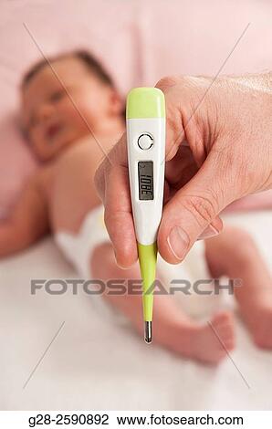 Adult hand holding a medical thermometer, with blurred baby in the background View Large Photo Image Stock Image - Adult hand holding a medical thermometer, with blurred baby in the background. Fotosearch