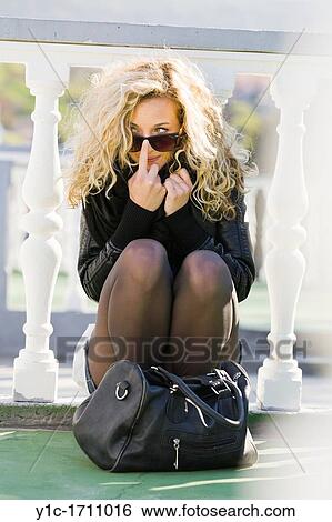 Stock Photograph - Attractive young woman adjusting glasses. Fotosearch