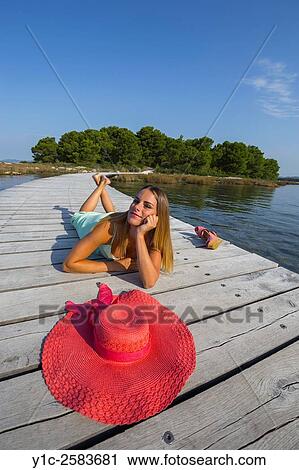 Stock Image - Attractive young woman and wide Red hat in foreground. Fotosearch