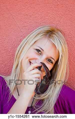 Stock Image - Attractive young woman happy and shy is hiding after her hand. Fotosearch
