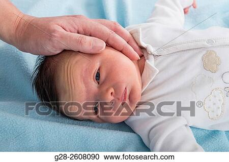 Baby boy 2 weeks old, looking worried, with father's hand on his head to soothe and comfort him View Large Photo Image Stock Image - Baby boy 2 weeks old, looking worried, with father's hand on his head to soothe and comfort him. Fotosearch