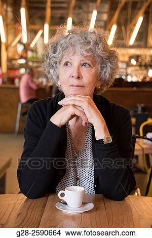 Beautiful senior woman, with grey hair, happy looking, thoughtful, with head resting on her clasped hands, elbows on table, in a cafe, with a cup of coffee in front of her View Large Photo Image Picture - Beautiful senior woman, with grey hair, happy looking, thoughtful, with head resting on her clasped hands, elbows on table, in a cafe, with a cup of coffee in front of her. Fotosearch