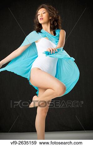 Beautiful young woman dancer in light blue cape and white leotard, with elegant lift against black background. View Large Photo Image Stock Photo - Beautiful young woman dancer in light blue cape and white leotard, with elegant lift against black background.. Fotosearch