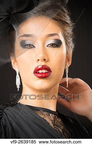 Stock Photography - Beautiful young woman in black dress and veiled hat, elegant portrait with direct look.. Fotosearch