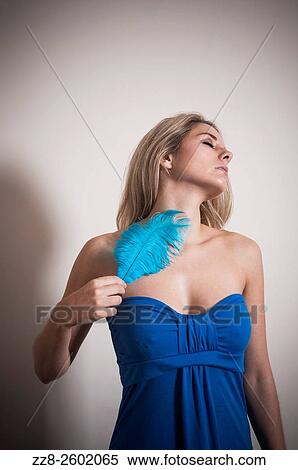Beautiful young woman with a blue feather touching her skin. View Large Photo Image Stock Photography - Beautiful young woman with a blue feather touching her skin.. Fotosearch
