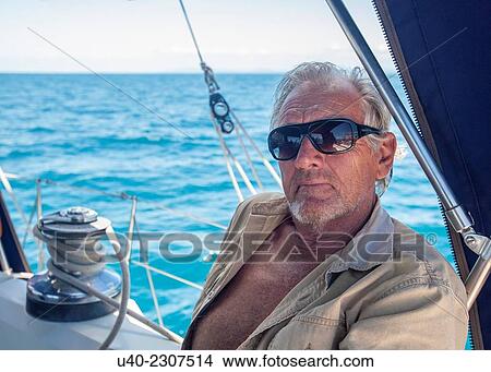 Picture - Belize, Captain in cockpit of sailboat.. Fotosearch