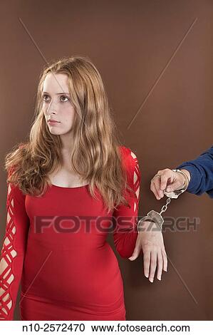 Stock Image - Blonde teenage girl handcuffed to a female hand.. Fotosearch