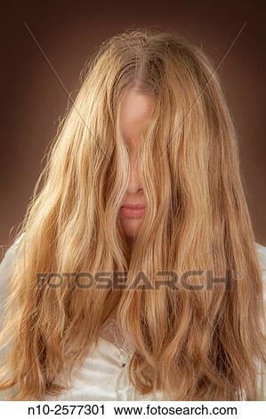 Stock Image - Blonde teenage girl's hair covering her face.. Fotosearch