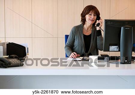 Stock Image - Breda, Netherlands. Reception-desk with female receptionist in a modern office building.. Fotosearch