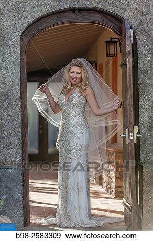 Stock Photo - Bride standing in an arched doorway before her wedding.. Fotosearch