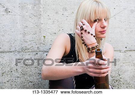 Stock Photo - Brushing tears young woman with a bottle in hand. Fotosearch