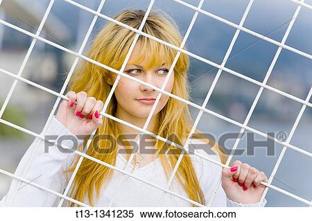 Captured behind a White metal fence young woman View Large Photo Image Stock Photography - Captured behind a White metal fence young woman. Fotosearch