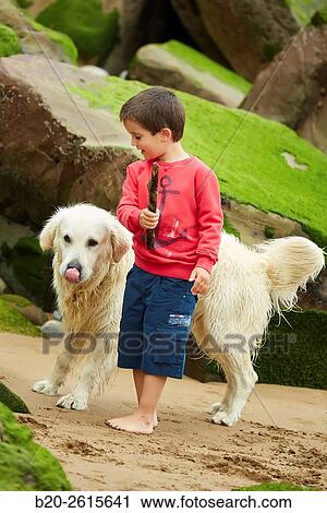 Stock Image - Child with dog playing on the beach. Getaria. Gipuzkoa. Basque Country. Spain. Fotosearch