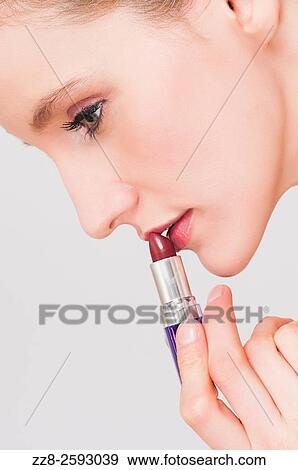Close up of a young woman applying make up lipstick. View Large Photo Image Stock Photo - Close up of a young woman applying make up lipstick.. Fotosearch