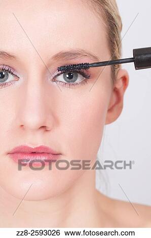 Close up of a young woman applying mascara to eyelashes. View Large Photo Image Stock Photograph - Close up of a young woman applying mascara to eyelashes.. Fotosearch