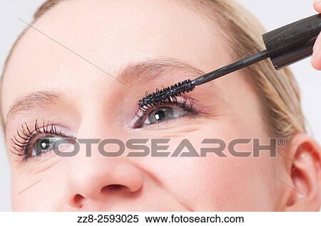 Close up of a young woman applying mascara to eyelashes. View Large Photo Image Stock Photography - Close up of a young woman applying mascara to eyelashes.. Fotosearch