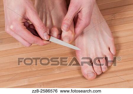 Stock Photograph - Close up of a young woman giving her feet a pedicure.. Fotosearch