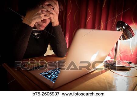Stock Photo - Closeup of a worried woman working with a computer at a time of rest, with the glasses on the table.. Fotosearch