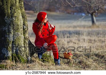 Picture - Country-girl in forest sitting on tree-root. Fotosearch