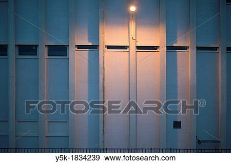 Stock Photo - Eindhoven, Netherlands. Outside wall of a factory with a burning streetlight, as seen from Central Station.. Fotosearch