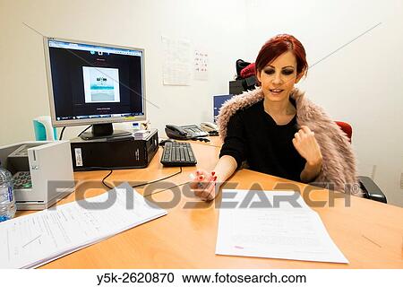Stock Image - European Parliament, Brussels, Belgium. Female employee to the Press Office signing a model release, while sitting at her workstation.. Fotosearch