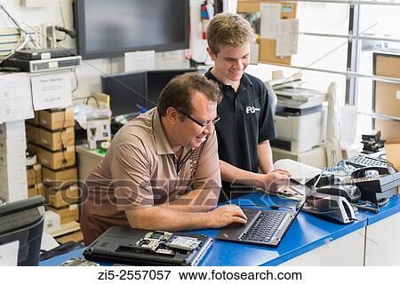 Stock Photo - Father is training his son in Computer repair shop. Fotosearch