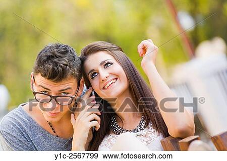Girl and boy cheek to cheek listen to cellphone View Large Photo Image Stock Photo - Girl and boy cheek to cheek listen to cellphone. Fotosearch