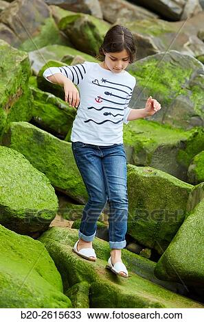 Stock Image - Girl playing on the rocks. Getaria. Gipuzkoa. Basque Country. Spain. Fotosearch
